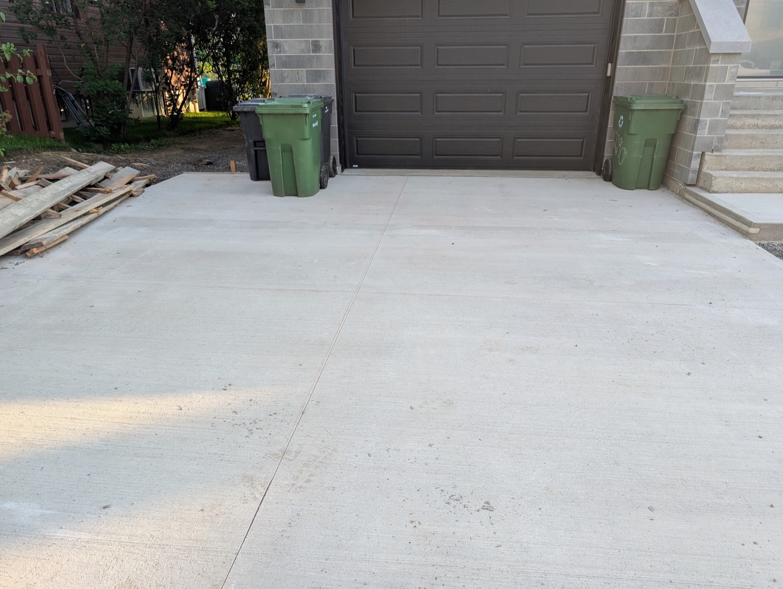 Dalle de béton coulée devant une porte de garage résidentielle